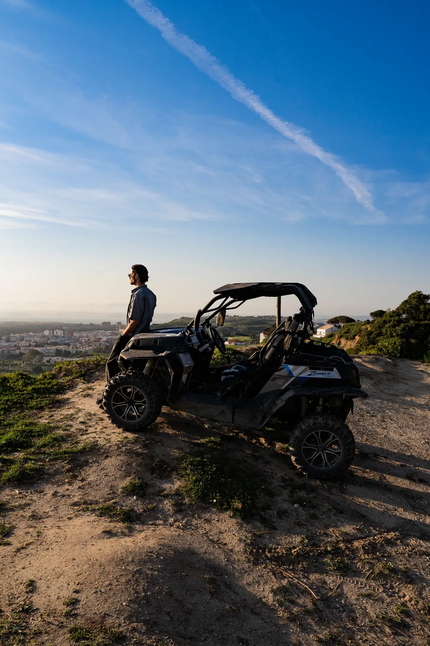 Rider beside a buggy on a clifftop overlooking the coast at sunset