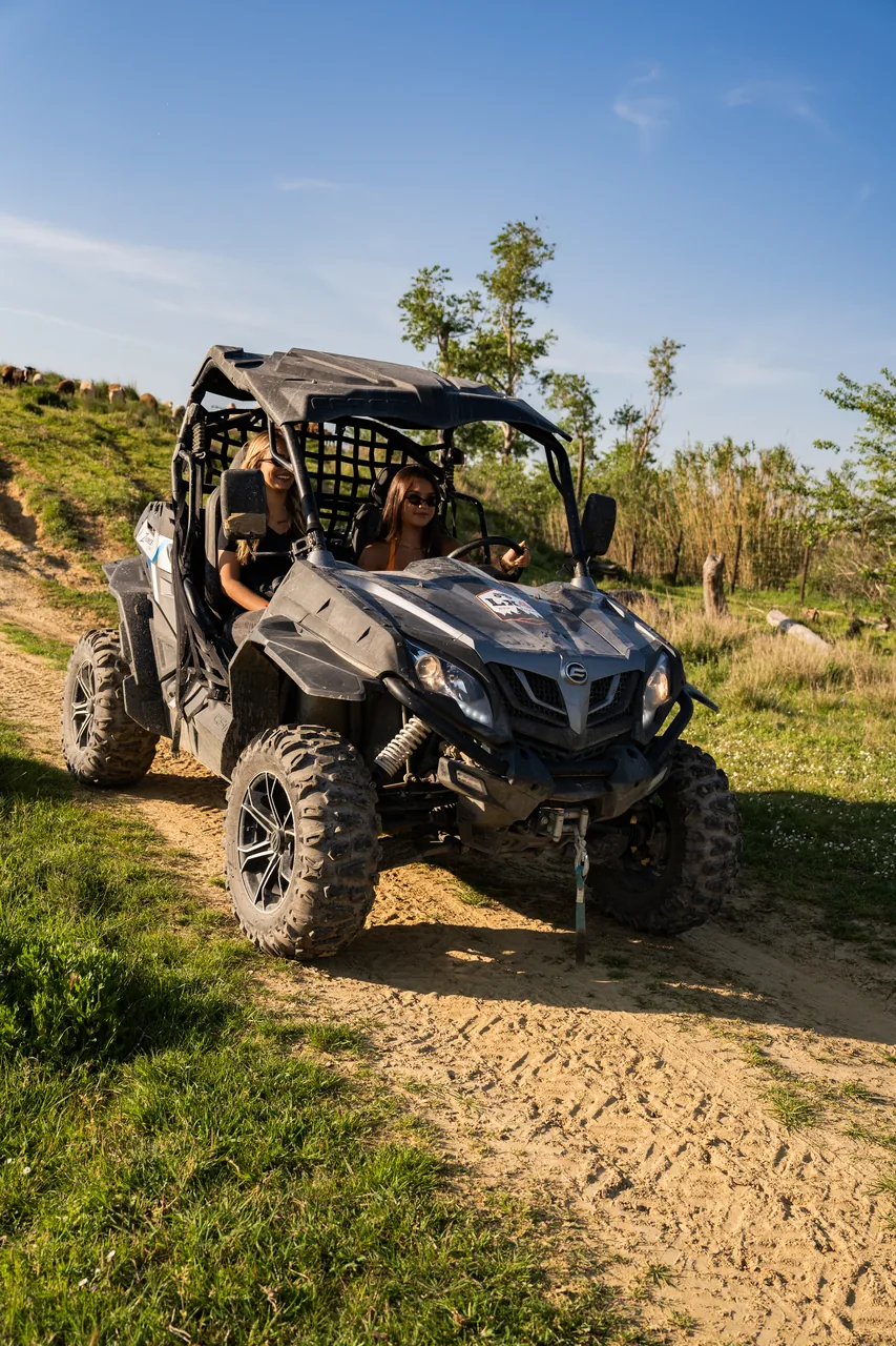 Two riders climbing a sandy hill in a buggy at golden hour