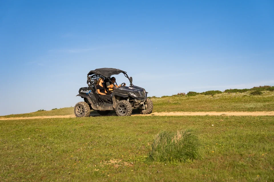 Buggy cruising over a green hilltop under blue sky