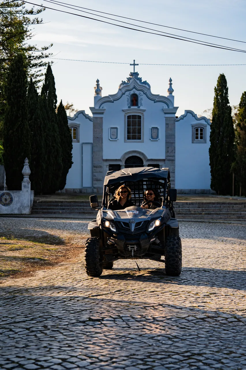 Buggy passing a whitewashed village church on cobblestones