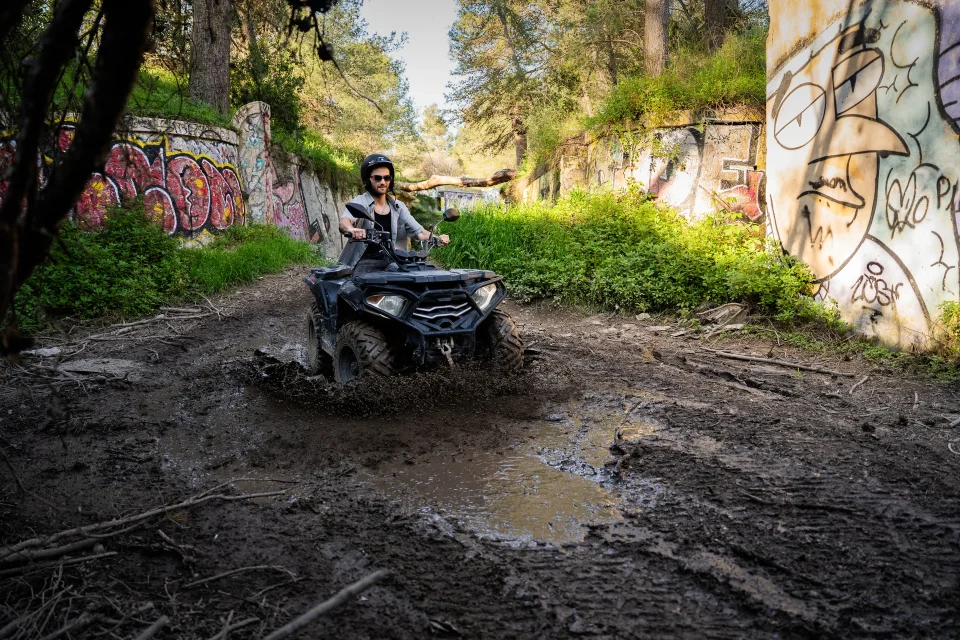 Quad splashing through a muddy graffiti trail